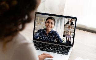 Person looking at laptop screen showing participants in online meeting